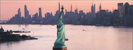  ??  ?? STANDING TALL: Dawn breaks over the Statue of Liberty in New York Harbor as the US struggles to contain the coronaviru­s outbreak.
AFP