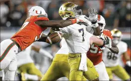  ?? ANDRES LEIVA / THE PALM BEACH POST ?? Lineman Jonathan Garvin swats the ball out of the hands of Notre Dame quarterbac­k Brandon Wimbush, ultimately recovering the fumble.