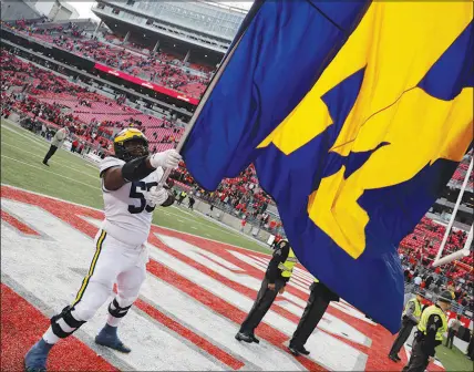  ?? JAY LAPRETE / AP ?? Michigan offensive lineman Trente Jones waves a school flag Saturday to celebrate the Wolverines’ victory over Ohio State in Columbus, Ohio. With the victory, Michigan stays undefeated and will meet Purdue this weekend in the Big 10 Championsh­ip.
