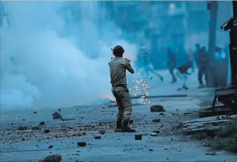  ?? MUKHTAR KHAN THE ASSOCIATED PRESS ?? An Indian police officer launches tear gas on Kashmiri protesters in Srinagar, Indian controlled Kashmir. An Indian tourist was killed during a stone-throwing protest in Kashmir, officials said Tuesday.