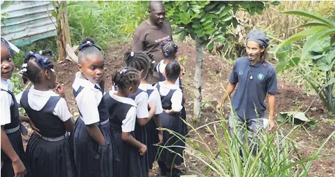  ?? PHOTOS BY AMITABH SHARMA ?? Lennocks Prince (left), a farmer in Shirley Castle, with Teppei Sato, JICA volunteer at Portland 4-H Clubs instructs students of the Shirley Castle Primary School, Portland before they begin planting saplings in their school garden.