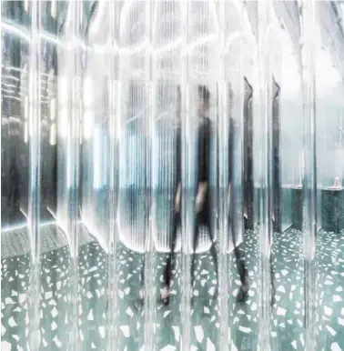  ??  ?? Above: Fitting rooms are enclosed by acrylic tubes, which create distorted visual effects. Within, green velour curtains allow for privacy. Opposite: The adjustable garment hanging system consists of frosted acylic rods connected by scaffoldin­g joints. Green marble bases vary in size depending on their use as display stands, benches or storage platforms.