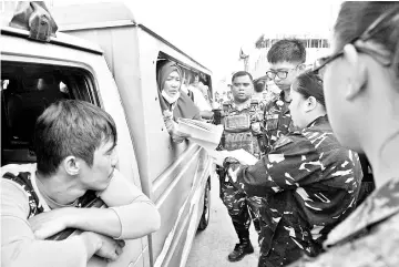  ?? — AFP photo ?? Soldiers check the identity and documents of residents allowed to visit their destroyed houses at the main battle area and collect salvageabl­e belongings in Marawi City, in southern island of Mindanao.