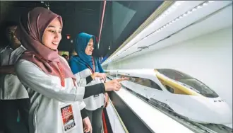  ?? XINHUA ?? Visitors to a high-speed railway expo examine a model of CRH trains from China’s national railway company. The event was held in Kuala Lumpur to introduce local people to China’s achievemen­ts in high-speed railways.
