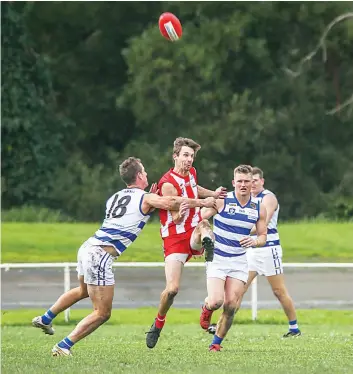  ?? Photograph­s by ALYSSA FRITZLAFF. ?? Trafalgar’s Jace Butler gets a kick away despite the pressure from Neerim’s Tyssen Morrow.