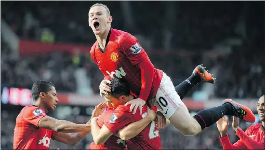  ?? — GETTY IMAGES ?? Manchester United’s Wayne Rooney leaps on Robin van Persie after his teammate scored against Arsenal.