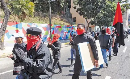  ??  ?? Militantes.
Jóvenes enmascarad­os marcharon el martes en Caracas en apoyo al presidente Maduro.