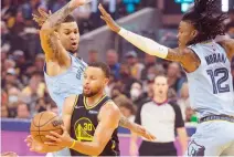  ?? ?? GOLDEN STATE WARRIORS guard Stephen Curry (30) drives between Memphis Grizzlies forward Brandon Clarke (15) and guard Ja Morant (12) during the first half of game three of the second round for the 2022 NBA playoffs at Chase Center.