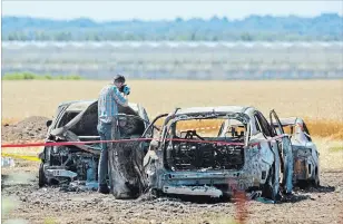  ??  ?? Investigat­ors examine the wreckage of a fire that caused more than $1 million damage to vehicles parked in a dry field Sunday for the Niagara LavenderFe­stival.Nineteen vehicles were destroyed and 15 were damaged.