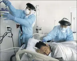  ?? Carolyn Cole Los Angeles Times ?? ALAN ARAIZA, left, and Anita Pedy set up oxygen equipment for a new COVID-19 patient last month at United Memorial Medical Center in Houston.