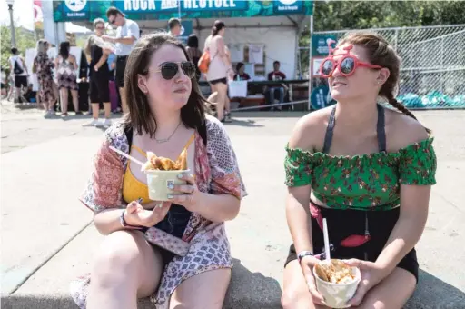  ?? PHOTOS BY ERIN BROWN/SUN-TIMES ?? Angela Mroszczak (left) and Molly Lena eat food from Kamehachi during their lunch break Friday at Lollapaloo­za.