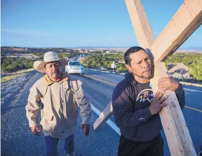  ?? EDDIE MOORE/JOURNAL ?? Jorge Martinez of Santa Fe carries a cross along N.M. 503, accompanie­d by Jaime Gonzales, on the annual pilgrimage of Catholics in New Mexico to the Santuario de Chimayó on Good Friday.