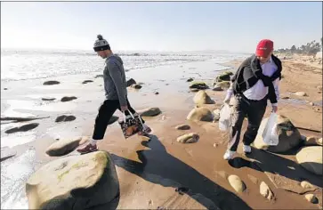  ?? Al Seib Los Angeles Times ?? TONY CHEETHAM, 71, and son Richard, 29, carry groceries along the beach Thursday after mudslides drove them from their home in Montecito’s Upper Village. At least 17 people have been killed and 100 homes razed.