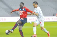  ?? - AFP photo ?? Lille’s French forward Jonathan David (L) and Marseille’ defender Yuto Nagatomo fight for the ball during the match at the Pierre-Mauroy Stadium in Villeneuve d’Ascq, northern France.