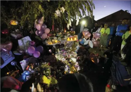  ?? ASSOCIATED PRESS ?? In this Oct. 22 photo, people gather at a memorial for missing 3-year-old Sherin Mathews at a tree behind her home in Richardson, Texas. Her father, Wesley Mathews, has told authoritie­s he ordered the child to stand next to a tree behind the fence at...