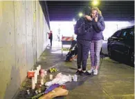  ?? SANDY HUFFAKER ?? Amie Zamudio and Nina Hermosura embrace in front of a makeshift memorial under the San Diego City College bridge on B Street downtown, east of Park Boulevard.