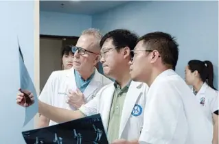  ?? PROVIDED TO CHINA DAILY ?? David Price Roye Jr. and his colleagues discuss a case at Shantou University’s Guangzhou Huaxin Orthopedic Hospital in Guangzhou, Guangdong province.