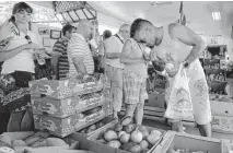  ?? [AP FILE PHOTO] ?? Shopper Miguel Ramirez smells a mango before purchasing at a local fruit store in the Little Havana area of Miami.