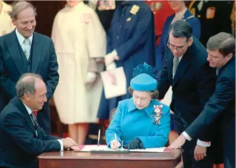  ?? Library and Archives Canada photo ?? Prime Minister Pierre Trudeau looks on as the Queen signs the Constituti­on Act with the Charter of Rights and Freedoms in front of the Peace Tower, April 17, 1982.