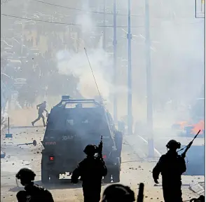  ?? AP/NASSER SHIYOUKHI ?? Israeli troops and Palestinia­n protesters face off Thursday in the West Bank town of Bethlehem.