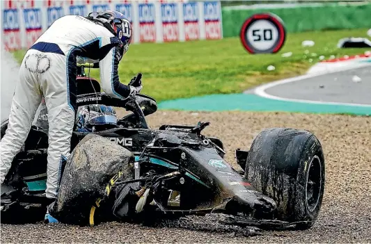  ?? Getty Images ?? George Russell, of the Williams Racing team, stands by the race car of Valtteri Bottas, of the Mercedes-AMG Petronas F1 team, still in the smoking car, after a crash. Both drivers were uninjured.