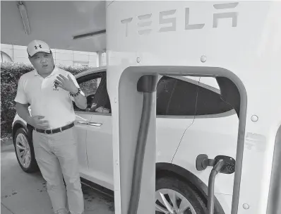  ?? AP Photo/Ng Han Guan ?? ■ Junhua Shan chats about privacy near his white Tesla while charging it June 22 in Shanghai. When Shan bought his white Tesla Model X, he knew it was a fast, beautiful car. What he didn’t know is that Tesla constantly sends informatio­n about the precise location of his car to the Chinese government. Automakers selling electric vehicles in China send a constant feed of informatio­n about the location of cars to the government, potentiall­y adding to the rich kit of surveillan­ce tools available to the regime as President Jinping Xi steps up the use of technology to track Chinese citizens.