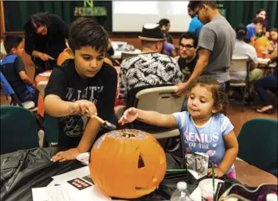  ?? PHOTO VINCENT OSUNA ?? Ryan Gutierrez, 8, (left) and Reanna Carmelo, 2, add finishing touches to their decorated pumpkin during Autism Support of Imperial County’s pumpkin carving and decorating event held Tuesday night at First United Methodist Church in El Centro.