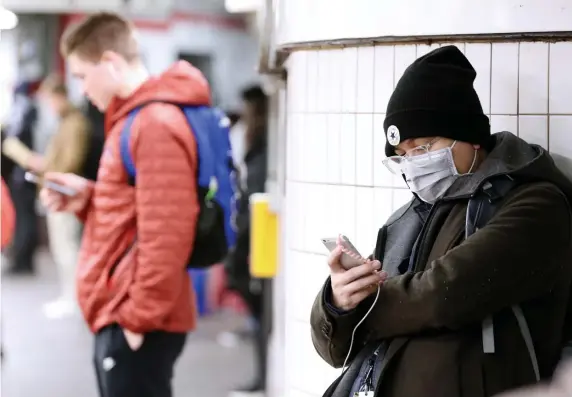  ?? ANGELA ROWLINGS / HERALD STAFF ?? SPREADING ‘RAMPANTLY’: A person wears a mask while waiting for a train at Park Street station. A Hainan Airlines flight from Shanghai arrives at Boston Logan Internatio­nal Airport. Logan is now diverting flights from Beijing and Shanghai.