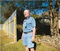  ?? ?? Tom Luckman, shown next to what he calls the “spite fence,” and some of his fellow Villages of West Neck residents have been at odds with the owner of the neighborin­g golf course since it closed in 2019.