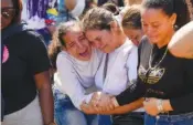  ?? AP PHOTO/ARIANA CUBILLOS ?? A sister of miner Santiago Mora, left, cries with other relatives as he is buried Thursday at the cemetery in La Paragua, Bolivar state, Venezuela.