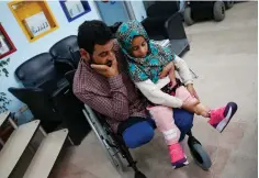  ?? Associated Press ?? ■ Maya Meri adjusts her prosthetic leg Thursday as she sits on her father Mohammed’s lap at a rehabilita­tion clinic in Istanbul.