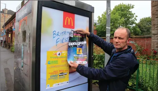  ??  ?? Govanhill Baths administra­tor Jim Monaghan attempts to cover some of the racist graffiti on a phone booth near the building Pictures: Mark Gibson