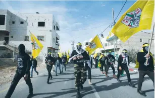  ?? (Mussa Qawasma/Reuters) ?? MASKED MEN take part in the funeral of Qusay Hasna al-Umour, who was shot dead on Monday by Border Police during a clash with protesters in the West Bank village of Tukua, near Bethlehem.