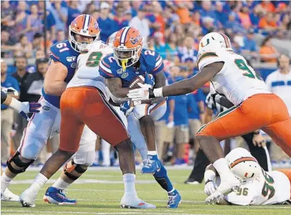  ?? MARK BROWN/GETTY ?? Florida’s Lamical Perine tries to break through the Miami defense in the first half Saturday night during the Gators’ 24-20 victory in Orlando.