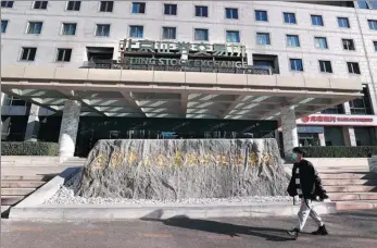  ?? CHEN XIAOGEN / FOR CHINA DAILY ?? A pedestrian walks past the Beijing Stock Exchange.