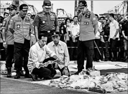  ?? ULET IFANSASTI/GETTY ?? Indonesia President Joko Widodo, center, holds a personal item from Lion Air flight JT 610 on Tuesday.