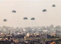  ?? (Jack Guez/AFP via Getty Images) ?? AN AIRDROP of humanitari­an aid over the Gaza Strip is shown in this photo taken yesterday from Israel’s southern border with the enclave.