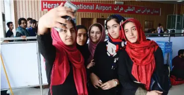  ?? Photo: AFP ?? Teenagers from the Afghanista­n Robotic House take pictures with a mobile phone at Herat Internatio­nal Airport before embarking for the United States yesterday.