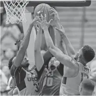  ??  ?? Connecticu­t’s Amida Brimah, left, and Kentan Facey, right, reach for a rebound against SMU’s Ben Moore, center, in Saturday’s game in Hartford, Conn. No. 17 SMU won 69-61.