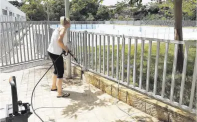  ?? JOSEP CARDA ?? Una operaria limpia con agua a presión el recinto de la piscina del Termet, que abrirán al público el sábado.