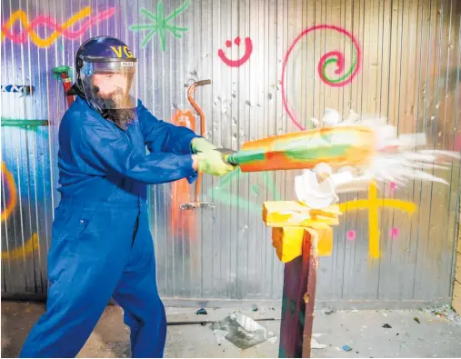  ?? Photos / Mark Mitchell ?? Smash Room owner Lloyd Bombell using a cricket bat to smash a plate in his Upper Hutt business.