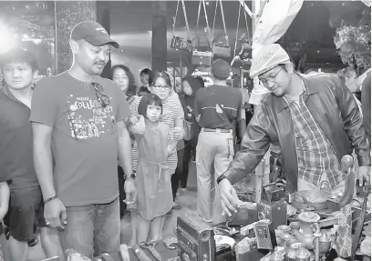  ?? — Gambar Bernama ?? CURI PERHATIAN: Sheikh Umar ( kanan) melihat jualan barangan antik di gerai sempena perasmian Festival Jazz Iskandar Puteri 2018, di Puteri Harbour, semalam.