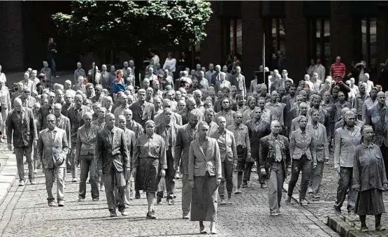  ?? Matthias Schrader/Associated Press ?? Vestidos de cinza e em silêncio para simular mortos-vivos, manifestan­tes fazem protesto contra o G20 organizado por grupo de artistas em Hamburgo