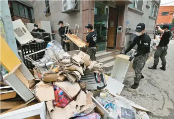  ?? JUNG YEON-JE/GETTY-AFP ?? Soldiers clear debris from a residentia­l area Wednesday in Seoul, South Korea. Two days of record-breaking rainfall around the capital region left thousands of buildings and roads damaged and at least 10 people dead with seven others still missing. Another 4 to 12 inches of rain is forecast for the southern regions of the country through Thursday.