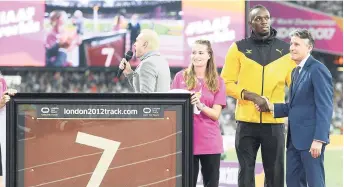  ?? RICARDO MAKYN/MULTIMEDIA PHOTO EDITOR ?? Usain Bolt (second right) shakes the hand of IAAF president Sebastian Coe after he was presented with a piece of the track at the London Stadium in London, England. This is where Bolt competed for the final time at the IAAF World Championsh­ips before...