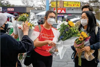  ?? ALYSSA POINTER/ ALYSSA. POINTER@ AJC. COM ?? Roula Abisamra ( center) and Chelsey ( right, last name withheld) are among those preparing to lay bouquets Wednesday at a makeshift memorial outside the Gold Spa in Atlanta, where three women were killed Tuesday.