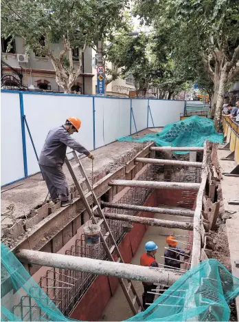  ??  ?? Workers lay undergroun­d pipeline yesterday on Wukang Road. — Wang Rongjiang