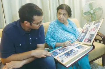  ?? (Akhtar Soomro/Reuters) ?? REHANA KHURSHEED HASHMI, 75, speaks with her grandson Zain Hashmi, 19, while looking through a family photo album at her residence in Karachi, Pakistan, last week.