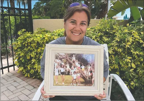  ?? (Courtesy Photo/Shaye Spector) ?? Camp Walden Director Robyn Spector holds a group photo from one of her first summers at camp. Spector, 48, would have been spending her 40th summer at Camp Walden.