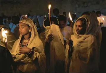  ?? AHMAD GHARABLI/GETTY-AFP ?? hold candles Saturday during the “Holy Fire” ceremony at Holy Sepulchre Church in Jerusalem’s Old City on the eve of Orthodox Easter. In the annual ceremony, a flame taken from Jesus’ tomb is used to light believers’ candles. Israel’s strict limits on event capacity dimmed the tradition for a second year.
decision by Italian Justice Minister Carlo Nordio to undertake a disciplina­ry investigat­ion, saying “we have to have clarity.”